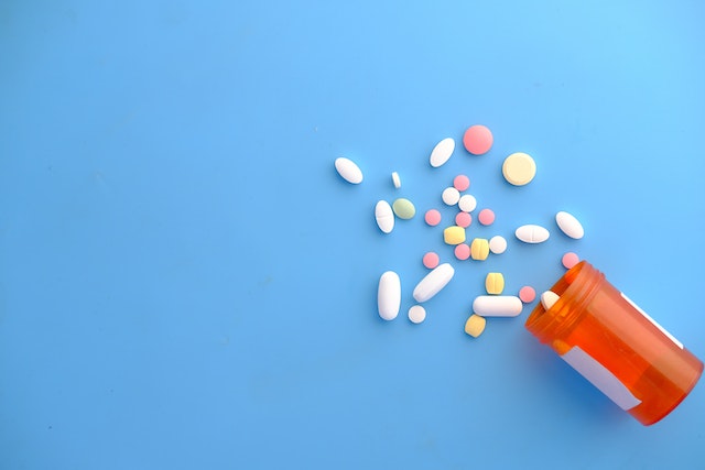 bottle spilling pills on blue background