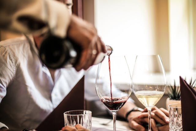 person pouring glass of wine